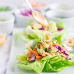 Spoon drizzling peanut sauce over lettuce wrap.