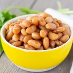 Cooked Peruvian beans in a small yellow bowl with cilantro on the side.