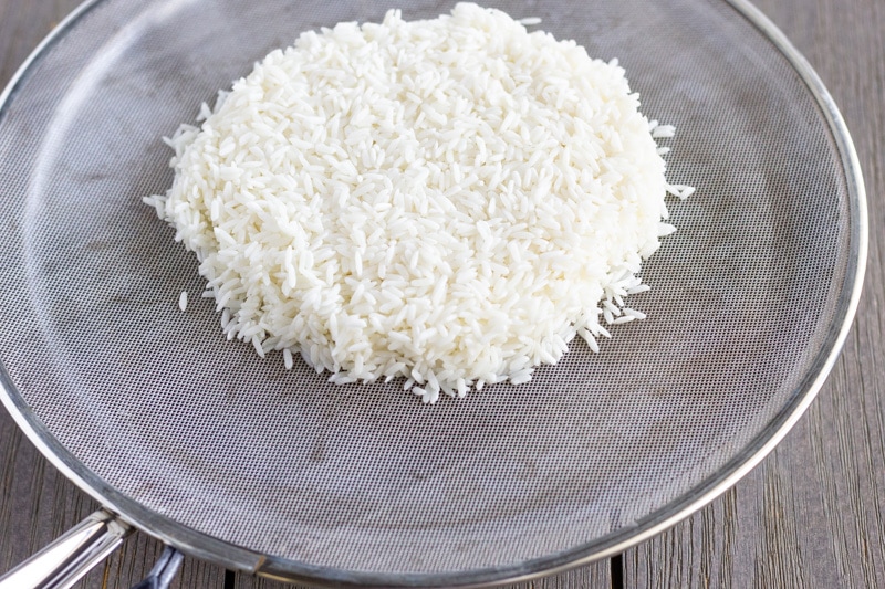 Saute pan with splatter guard as the cover, and a mound of sticky rice on top.