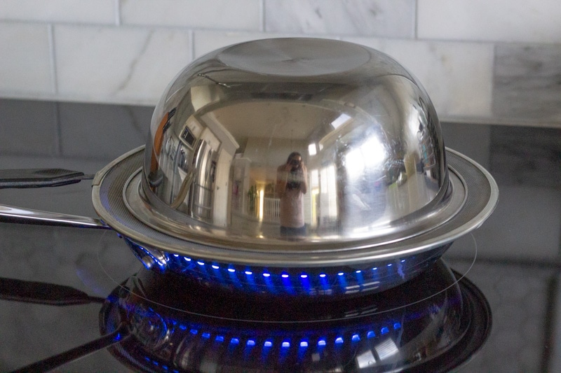 Pan on the stove with a stainless bowl covering the rice.